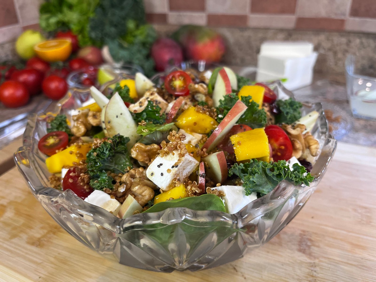 a colorful bowl of healthy salad with apple wedges, mango and kale