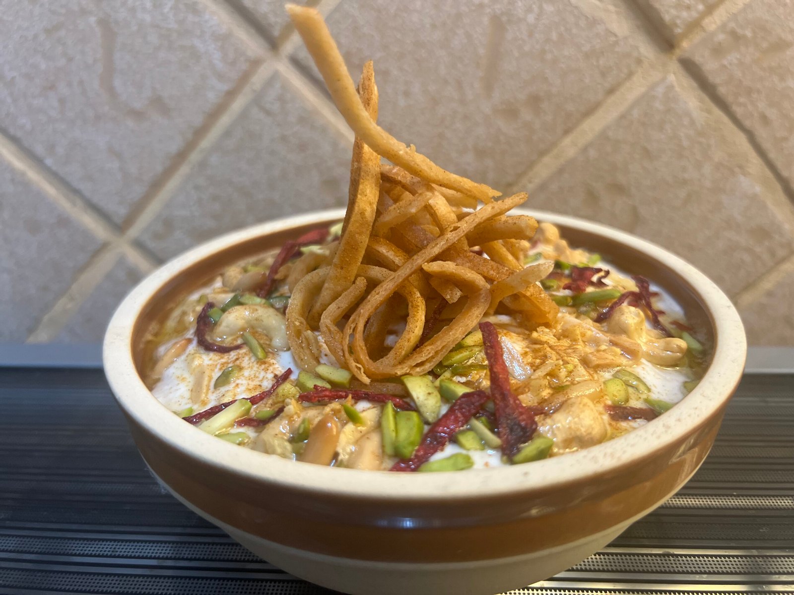 a bowl of chickpea fatteh decorated with fried tortilla and roasted nuts