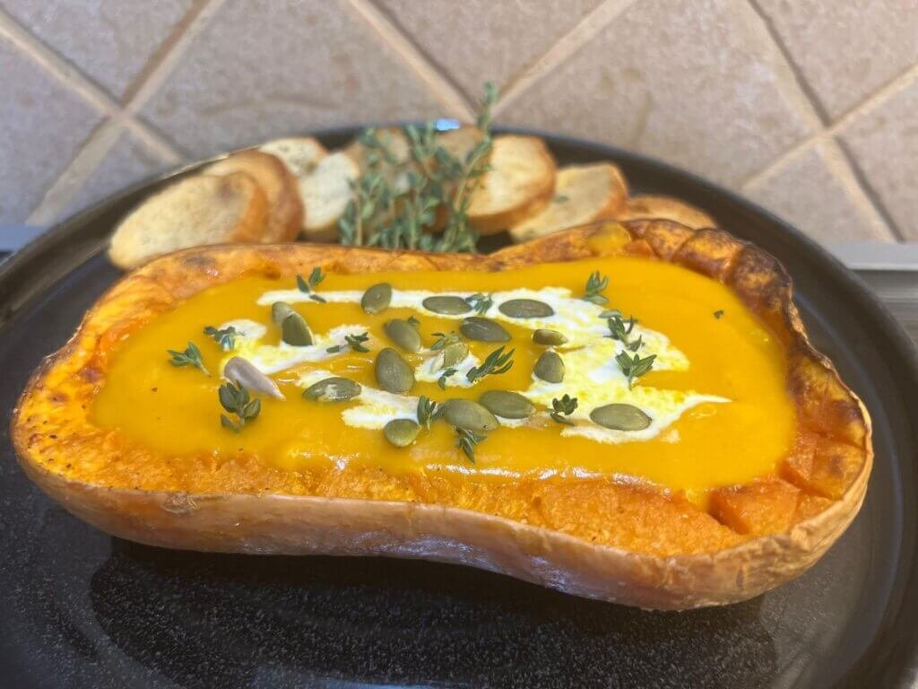 easy pumpkin soup recipe, the pumpkin is in a plate with the soup inside the pumpkin