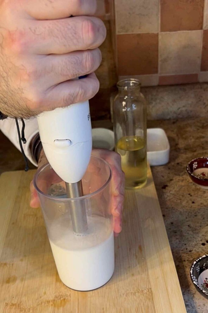 Preparing Lebanese garlic dip in a narrow container with a hand blender