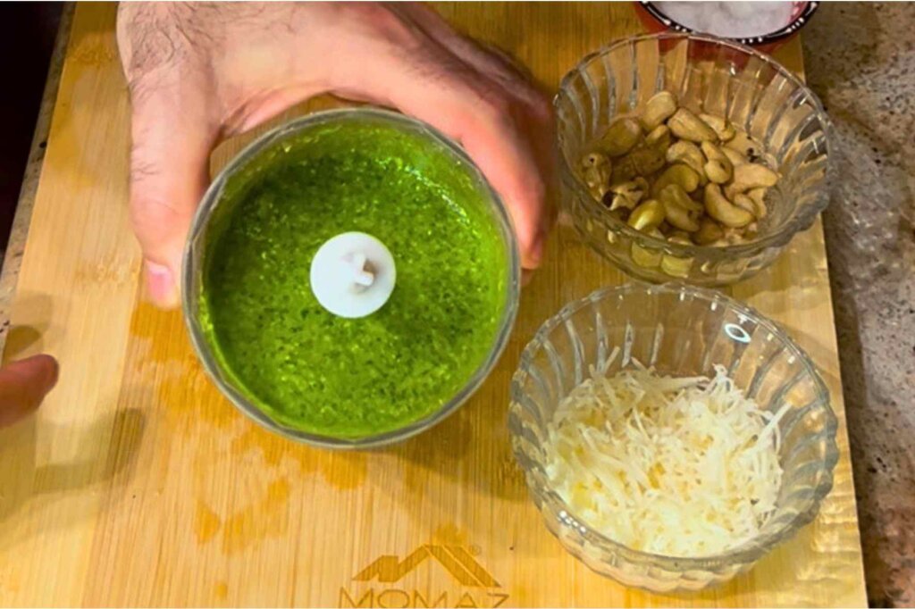 Freshly blended homemade pesto with cashews showing its vibrant green color before adding Parmesan cheese.