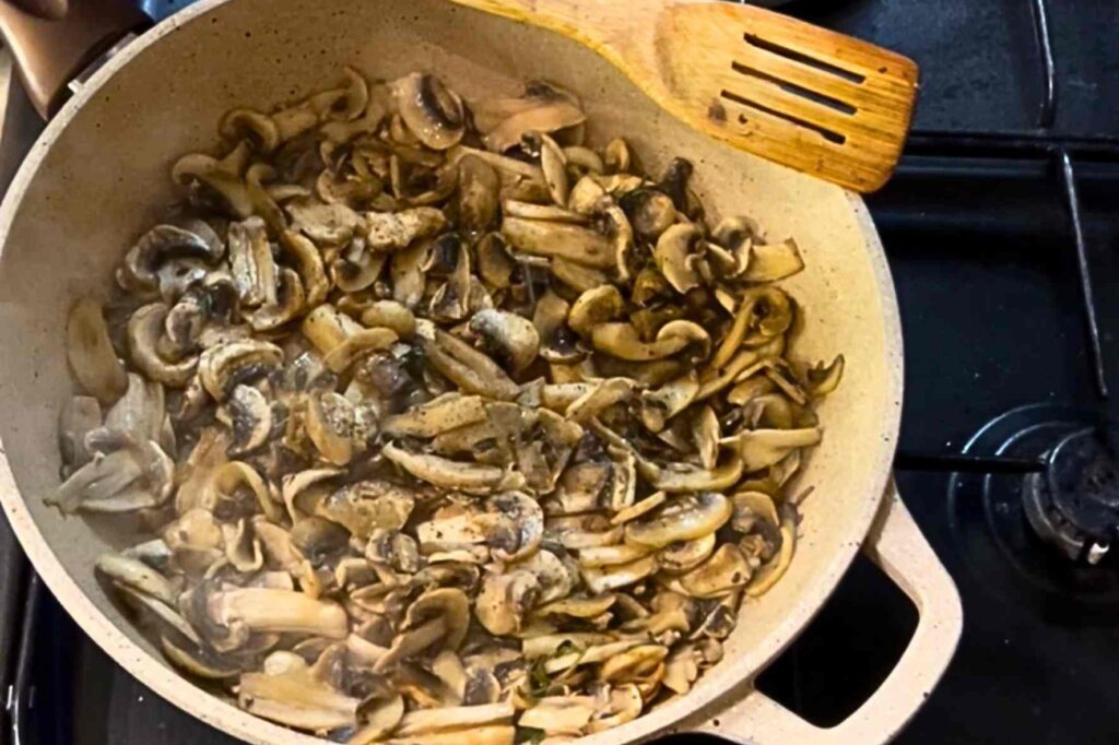 Fresh mushrooms cooking in a pot with onions and thyme for creamy mushroom soup