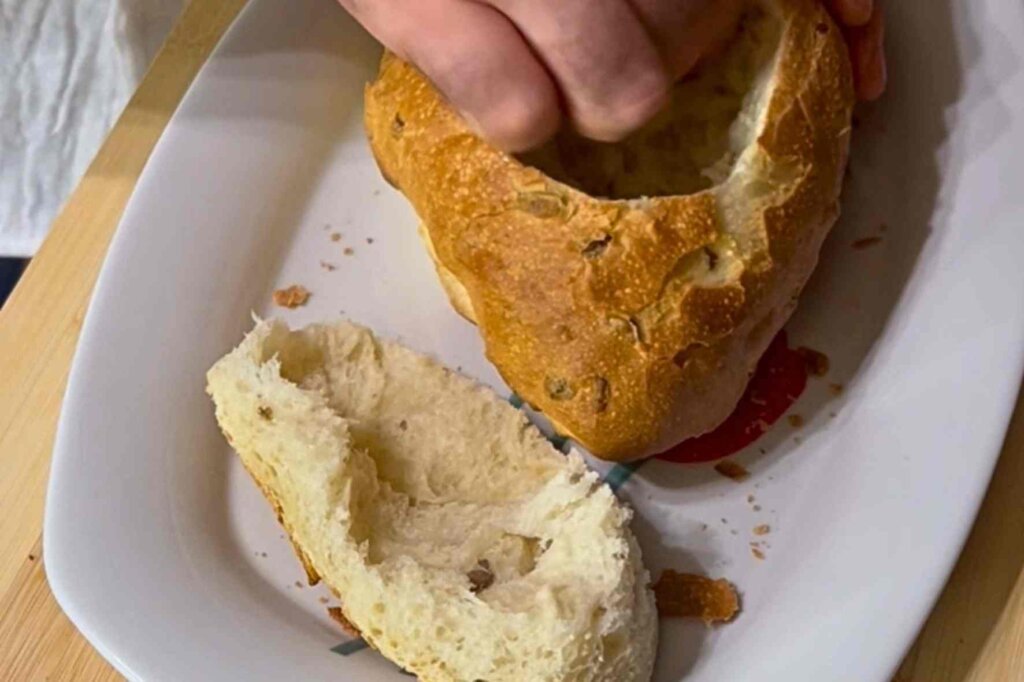 Removing the inside of a sourdough bread loaf to make a bread bowl for creamy mushroom soup