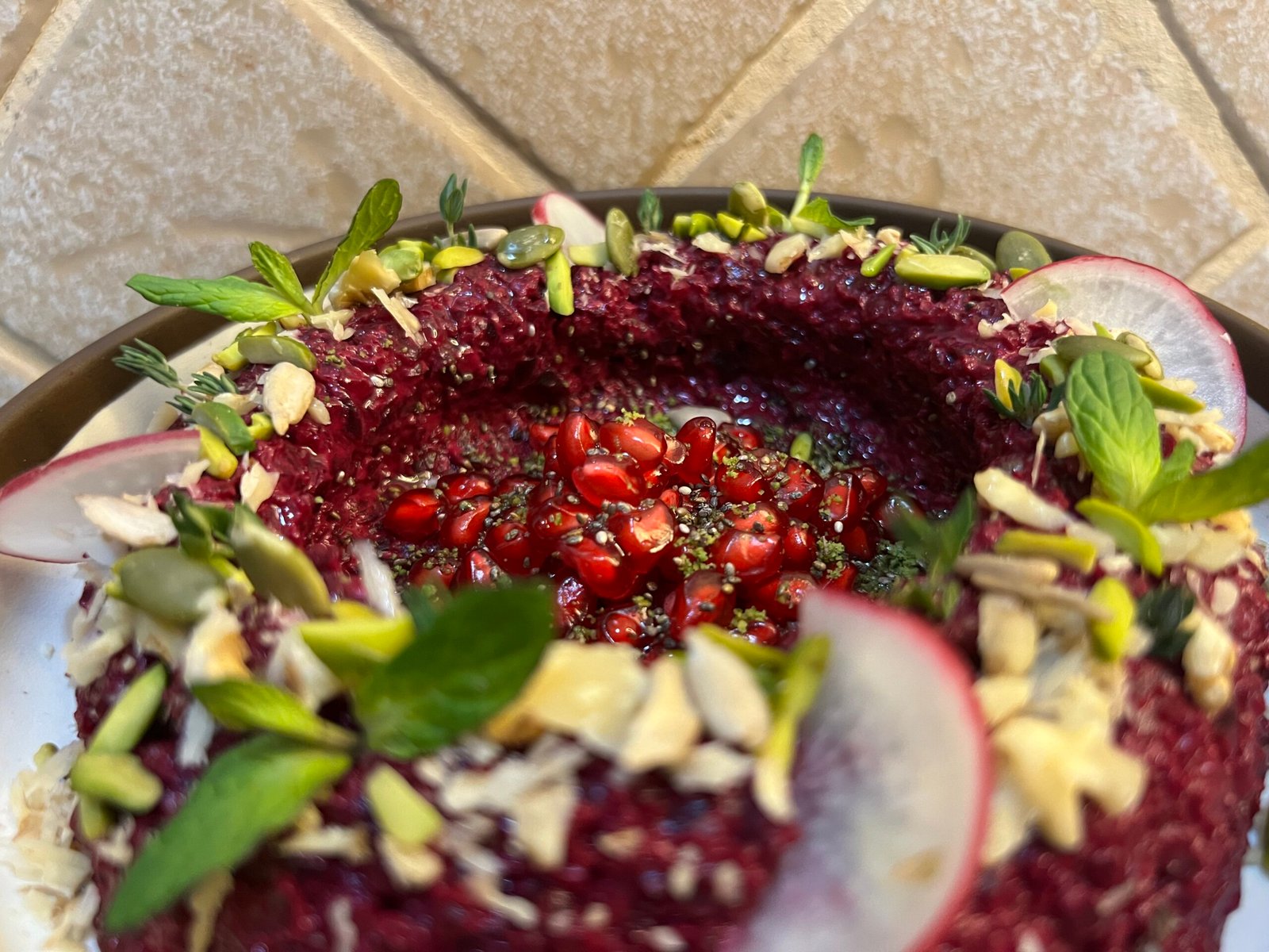 a dish of beetroot mutabal with mint, pistachios, seeds and radishes