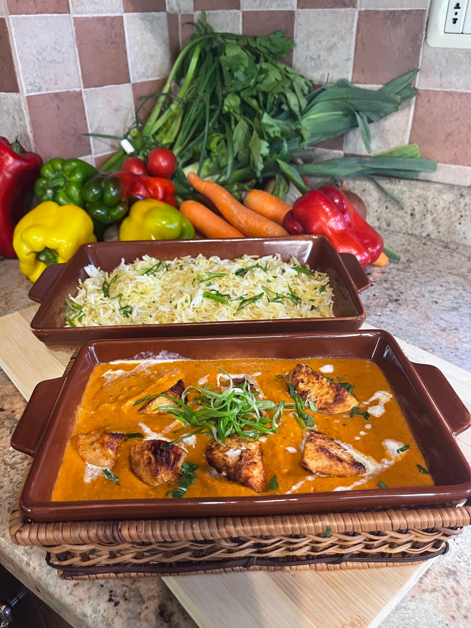 Plate of creamy butter chicken served with saffron basmati rice, garnished with herbs and rich orange sauce.