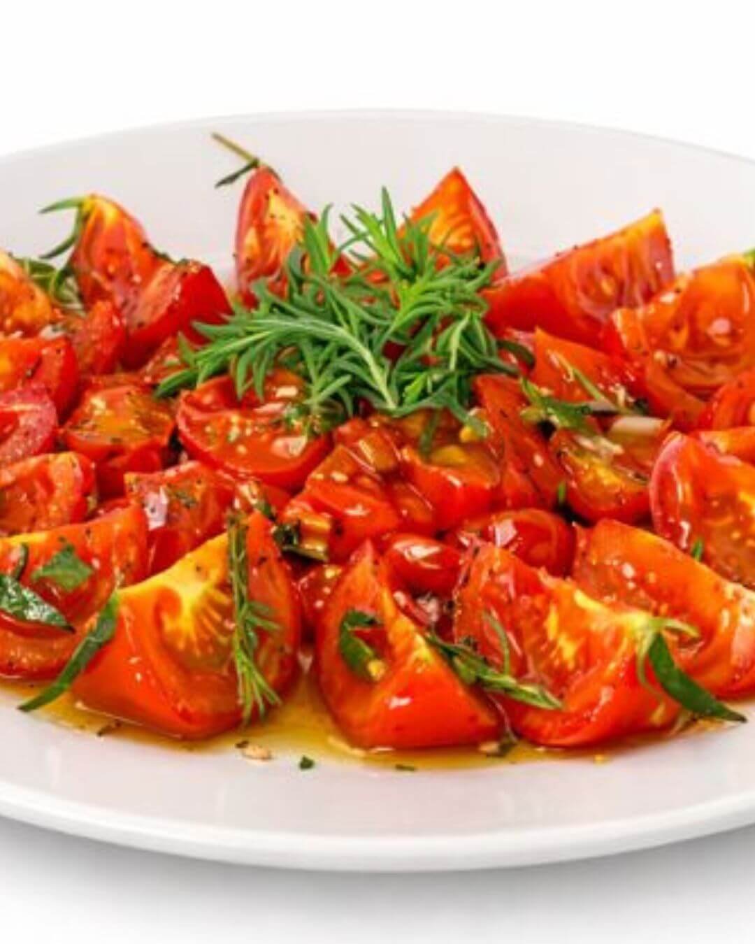Caramelized tomatoes cut into wedges, arranged on a plate, drizzled with olive oil and garnished with fresh thyme and herbs.