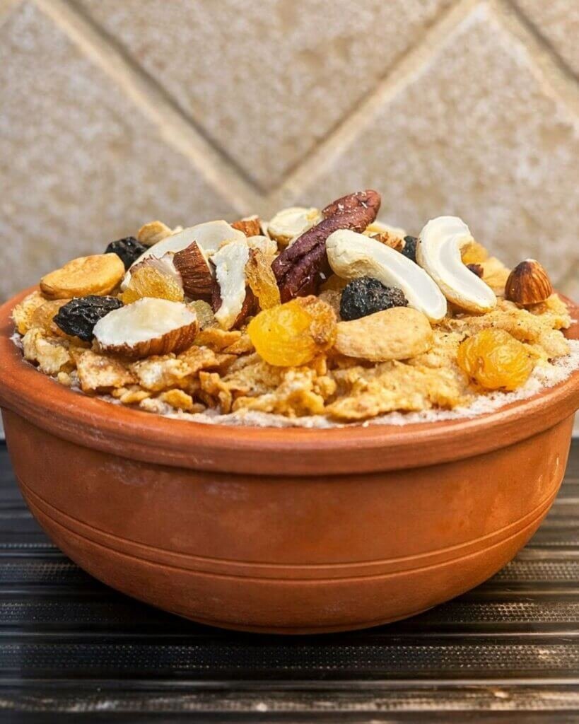 Umm Ali dessert served in a clay pot topped with mixed nuts, raisins, and dried fruits