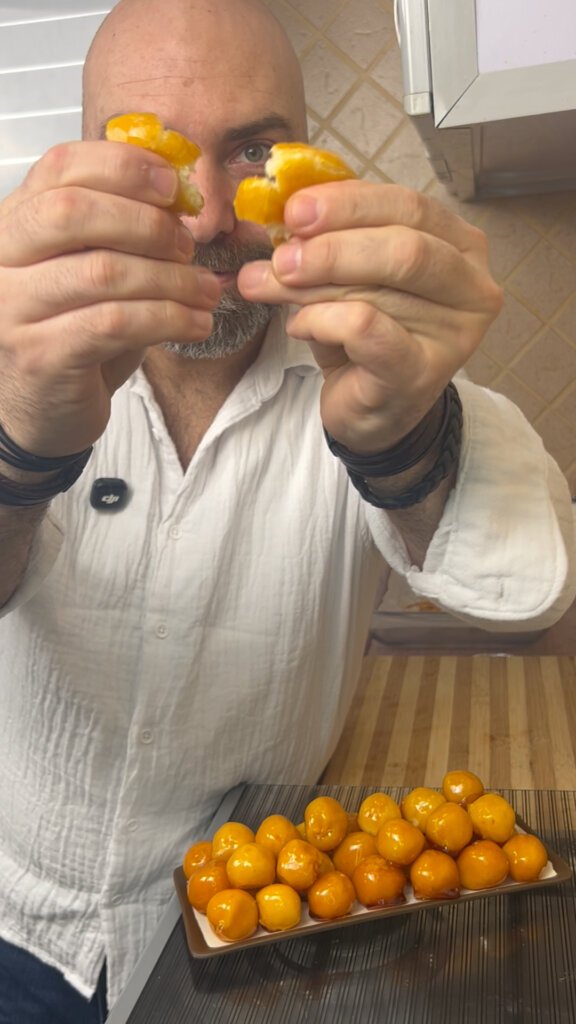 Chef breaking a bala baiana coconut candy in half showing the soft inside and crunchy caramel coating