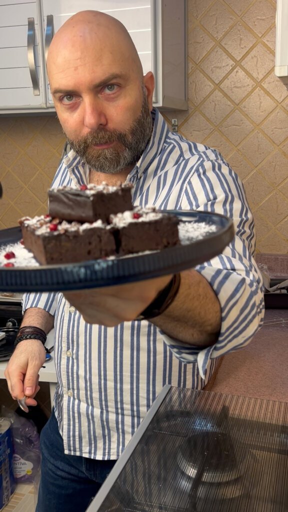 chef holding a plate of flourless sweet potato brownies topped with powdered sugar and chocolate chips