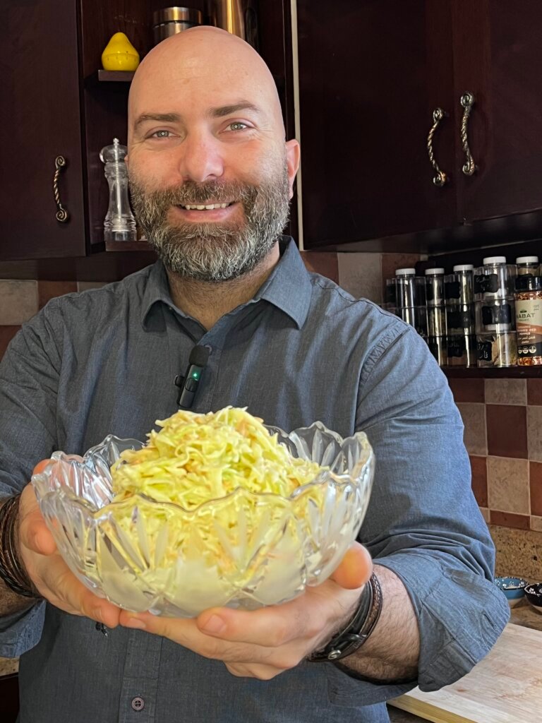 chef standing in the kitchen holding a bowl of delicious coleslaw