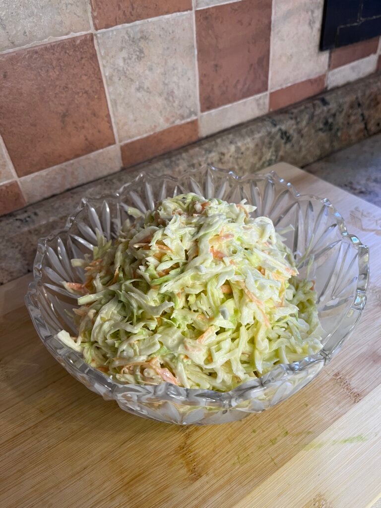 Close-up of creamy coleslaw salad showing finely shredded cabbage and carrots coated in a smooth dressing