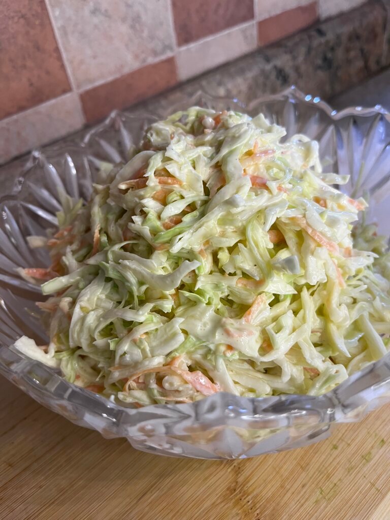 Bowl of creamy cabbage salad with shredded cabbage and carrots mixed in mayonnaise dressing