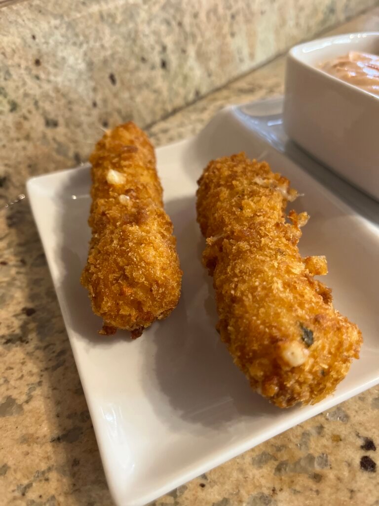 two crispy mozzarella sticks in a white plate