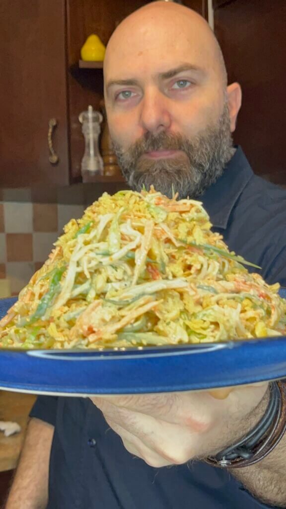 Chef François holding a plate of fresh kani salad with crab sticks, mango, cucumber, and creamy dressing