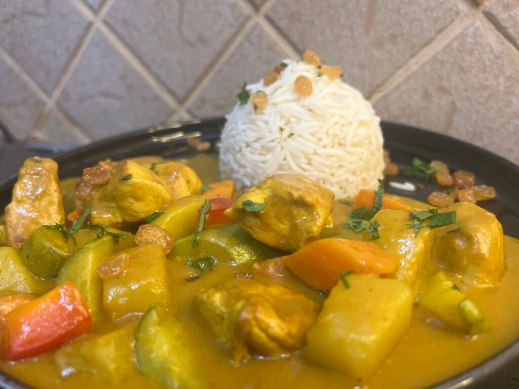 Plate of homemade chicken curry served with jasmine rice, showing creamy sauce and vegetables