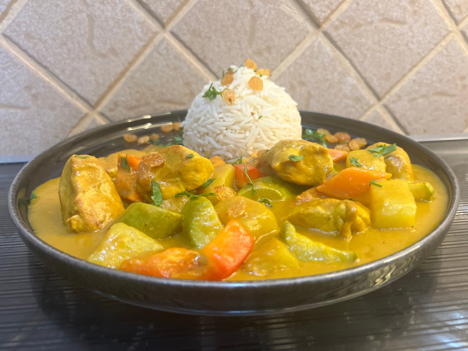 Plate of creamy chicken curry served with jasmine rice and vegetables, rich in spices and sauce