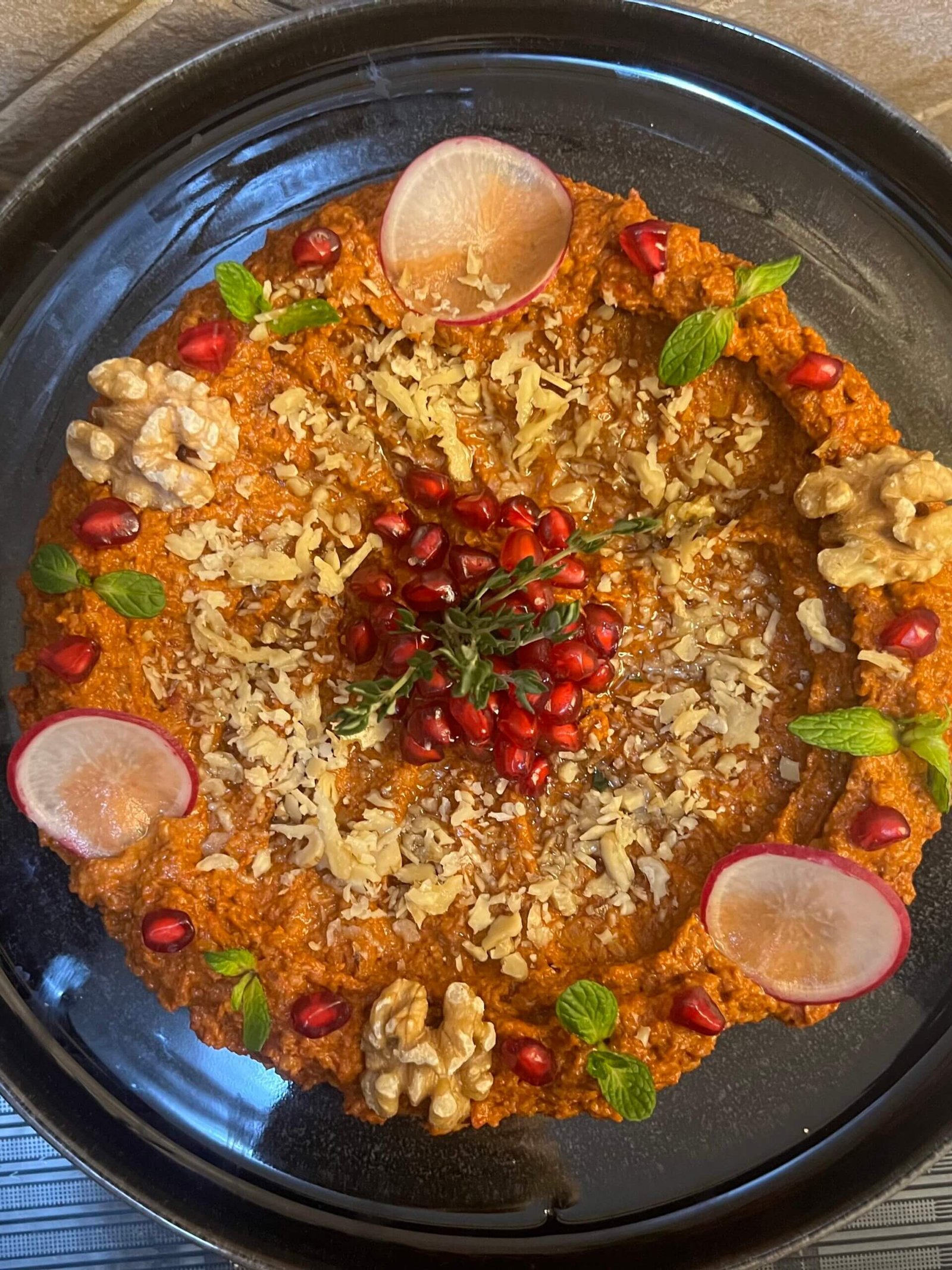 Top view of Muhammara dip in a bowl garnished with olive oil and walnuts