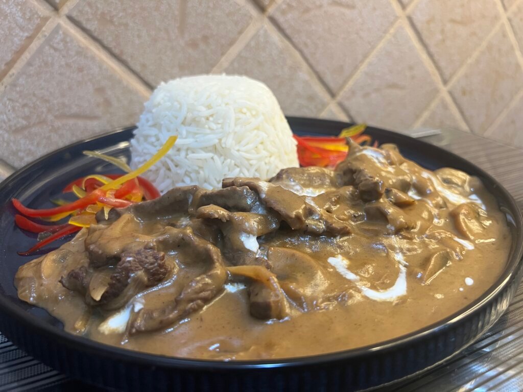 Creamy beef stroganoff with colored peppers on the side