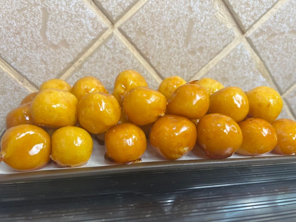 tray of bala baiana coconut candies coated in shiny golden caramel glaze close up