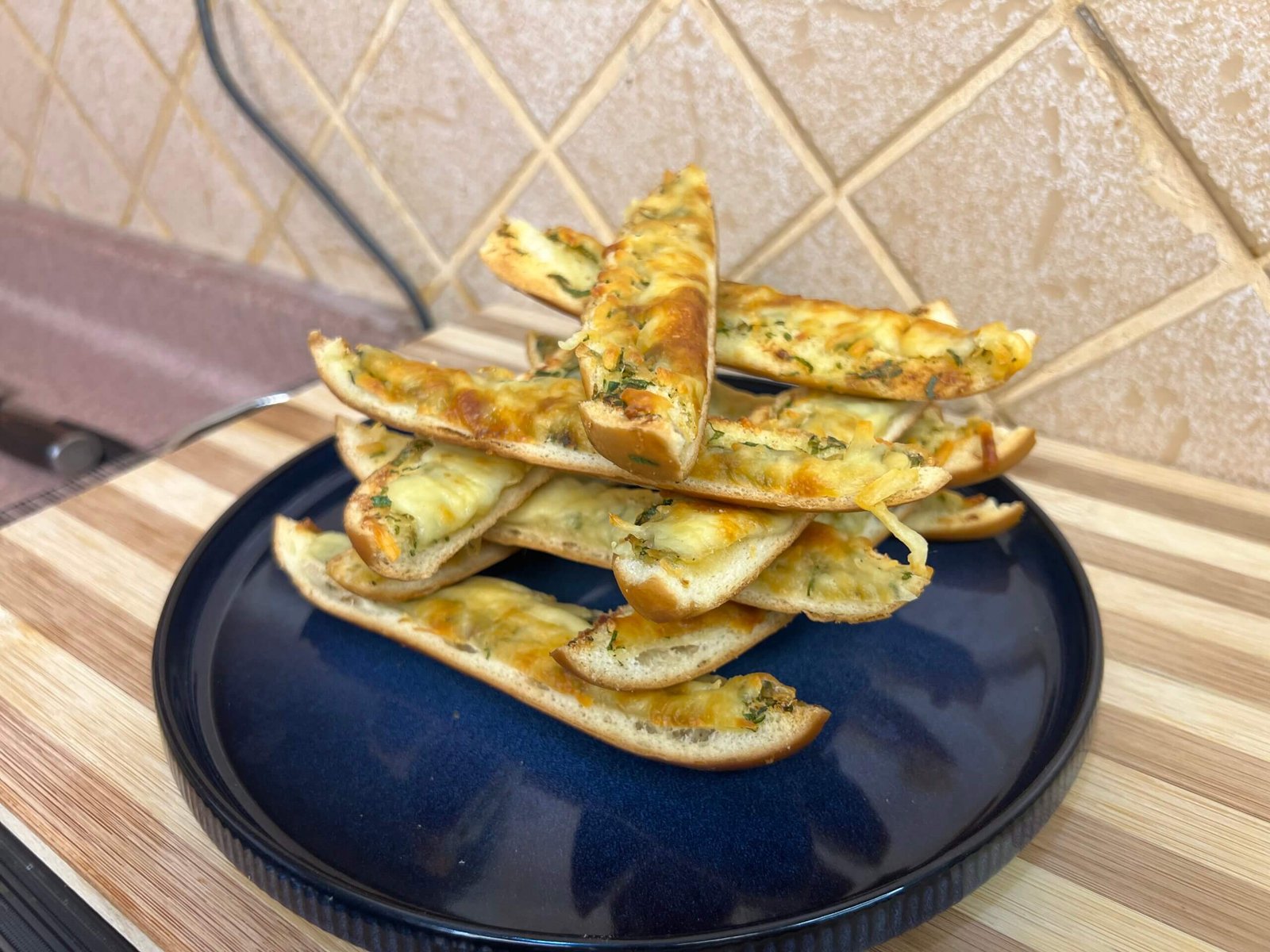 a blue plate placed on a wooden cutting board with cheese garlic bread in it