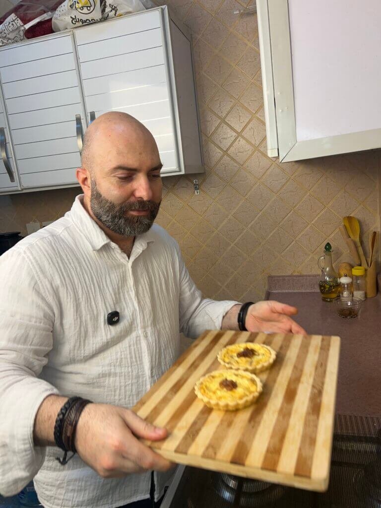 chef holding a wooden cutting board with 2 mini quiches