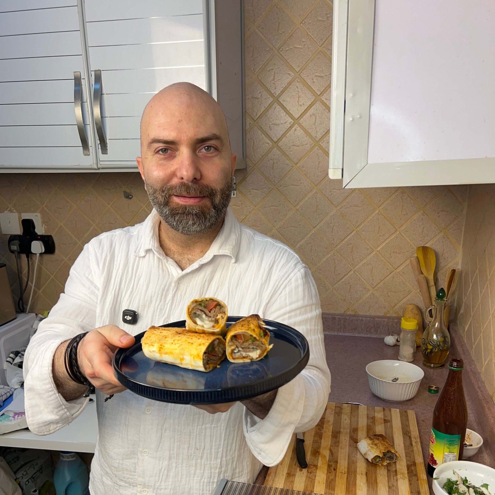 Chef holding a plate of homemade doner kebab wraps in a kitchen, showing juicy filling and crispy bread