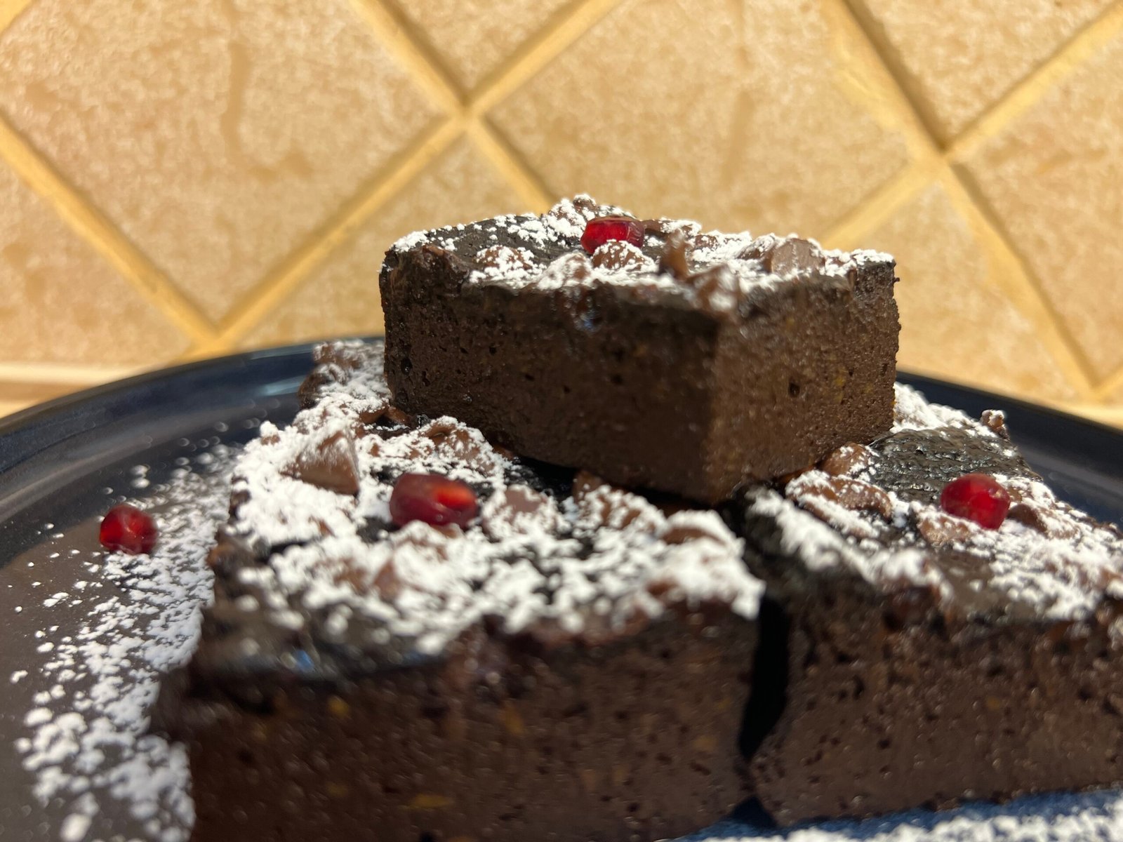 close up of sweet potato brownie topped with powdered sugar and chocolate chips on a plate