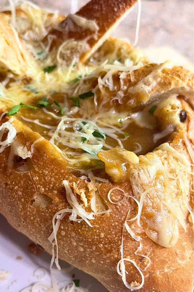 Close-up of French onion soup in a crusty bread bowl with melted cheese and toasted bread lid