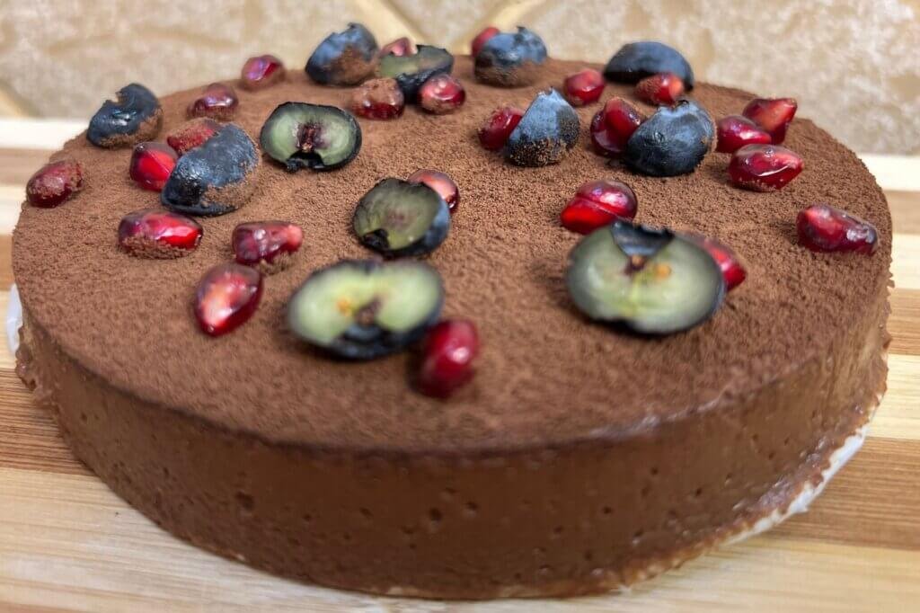 Smooth chocolate mousse cake made with apples and dark chocolate, topped with blueberries and pomegranate seeds