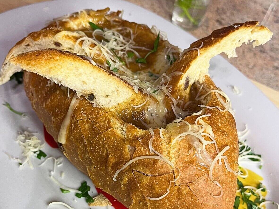 French onion soup served in a crusty bread bowl, topped with melted cheese and toasted bread slices
