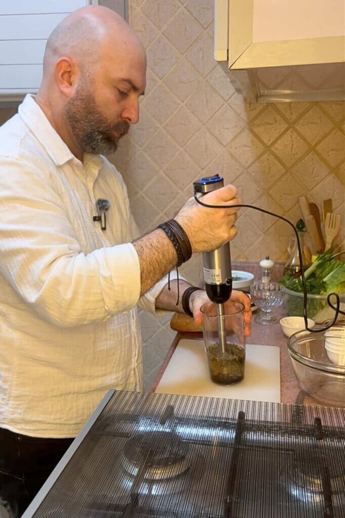 Chef François preparing homemade fattoush dressing using fresh ingredients in a kitchen.