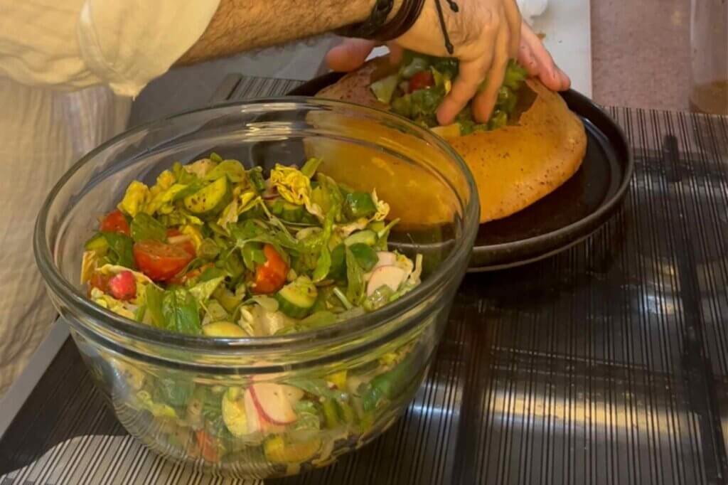 Fresh Lebanese fattoush salad being served inside traditional Arabic bread with crisp vegetables and herbs.