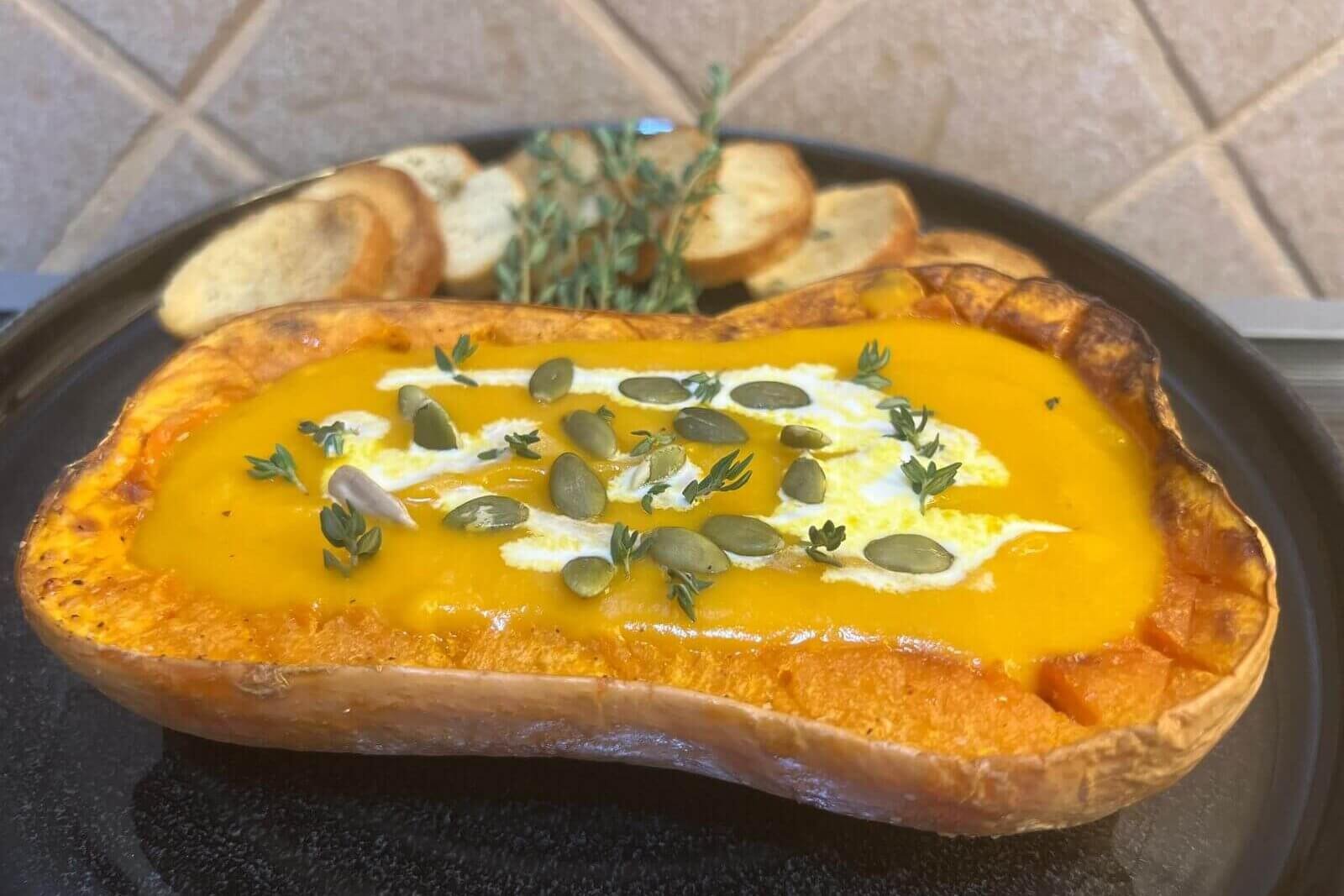 easy pumpkin soup recipe, the pumpkin is in a plate with the soup inside the pumpkin