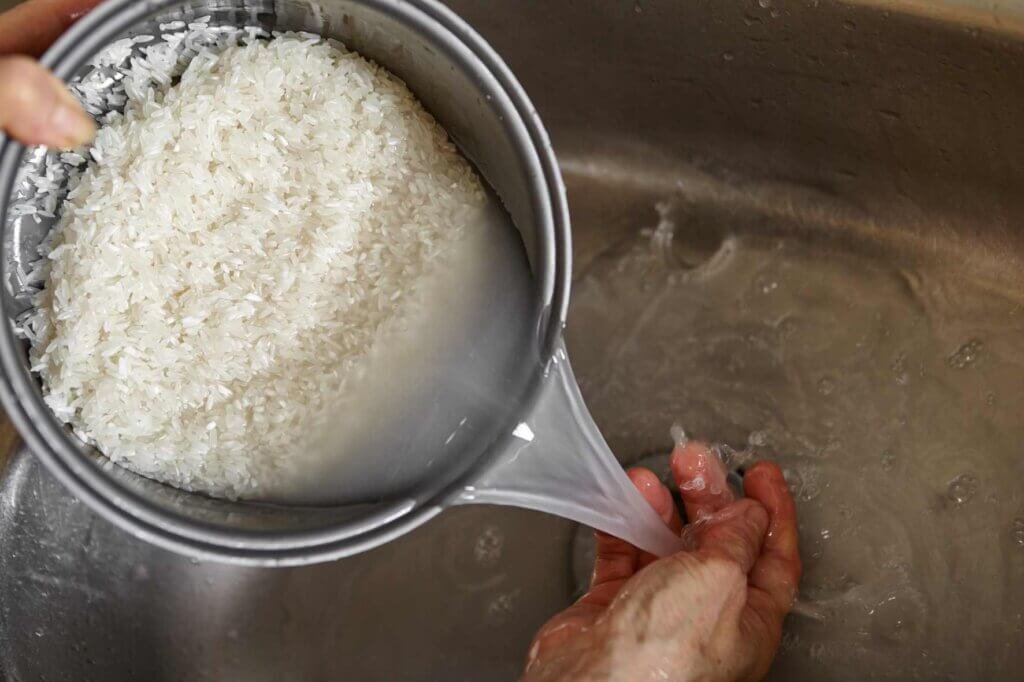 Rinsing white rice under water to remove excess starch before cooking