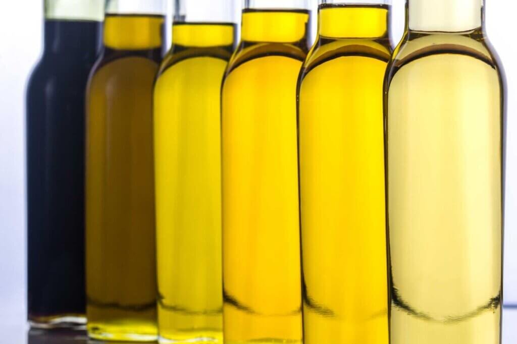 A row of bottles filled with different types of cooking oils, illustrating the variety of oils commonly used for deep frying and achieving crispy fried food.