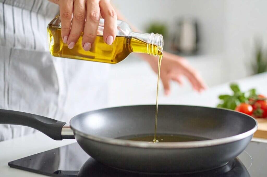 Cooking oil being poured into a frying pan, demonstrating the correct amount of oil for shallow frying foods until golden and crispy.