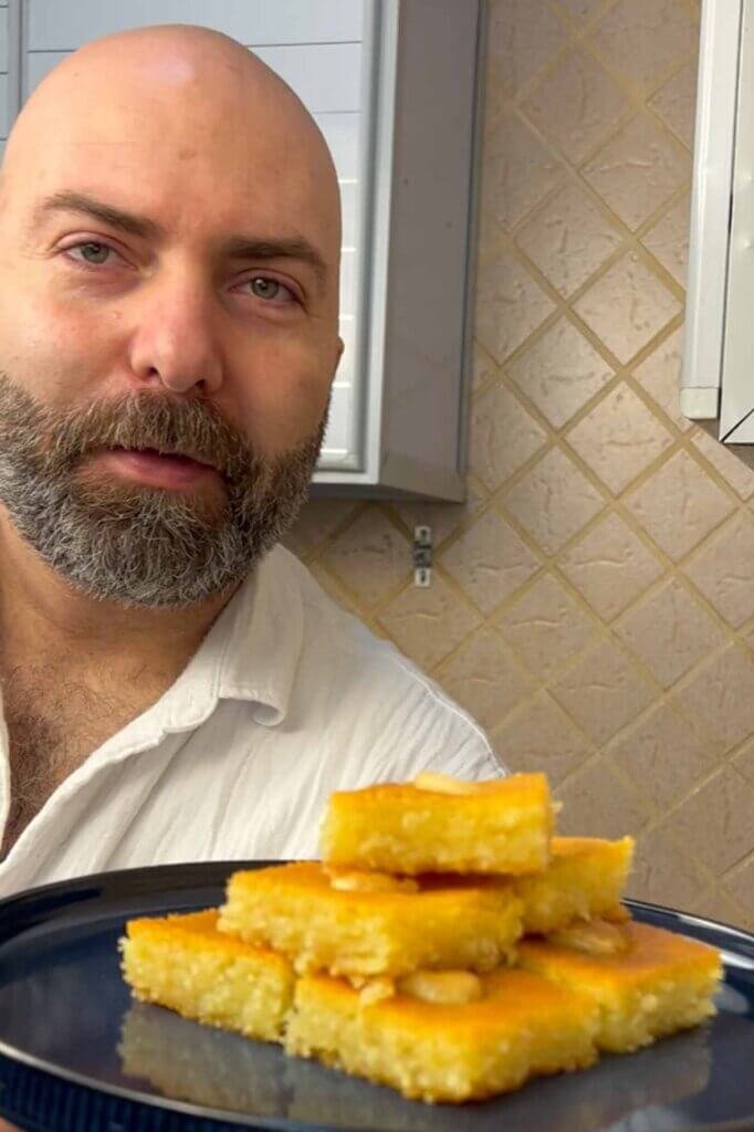 Chef François holding a plate of homemade Lebanese nammoura, a golden semolina cake soaked in syrup and topped with almonds.