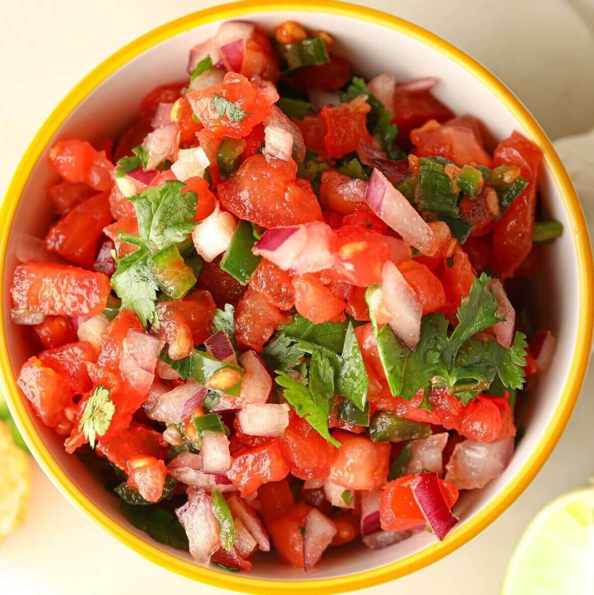 Overhead view of homemade Pico de Gallo made with diced tomatoes, red onion, jalapeños, and fresh cilantro in a bowl.