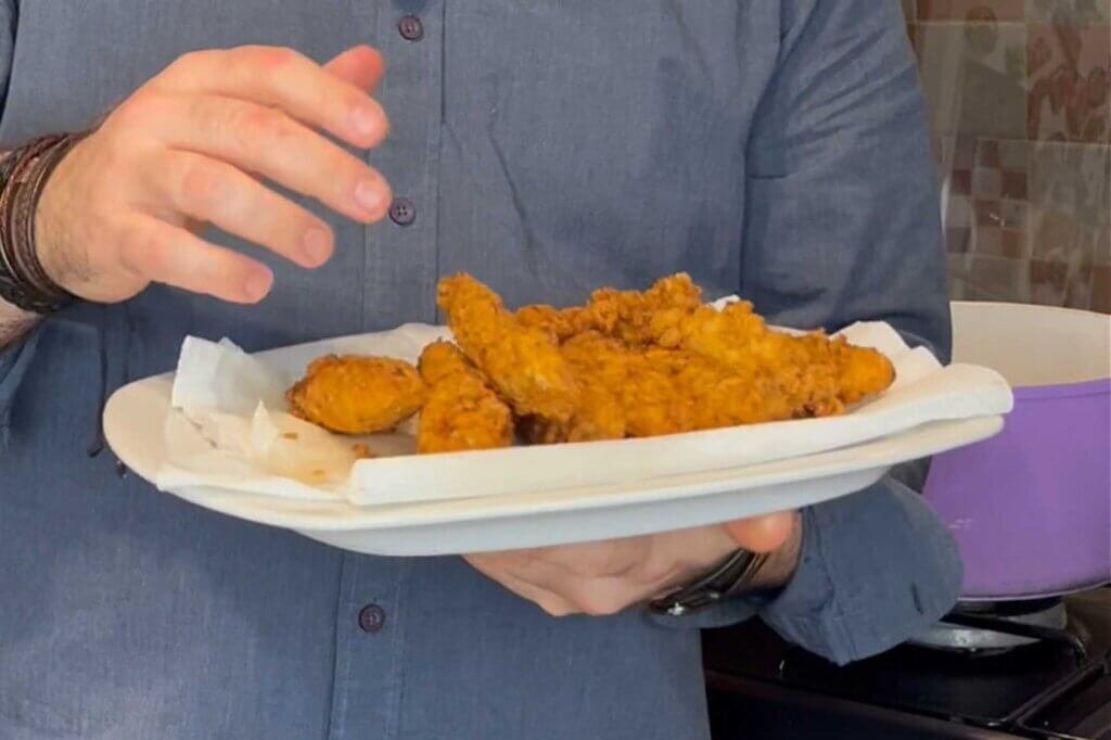 Chef François holding a plate of freshly fried homemade fish sticks, showcasing their golden crispy coating and restaurant-quality appearance.