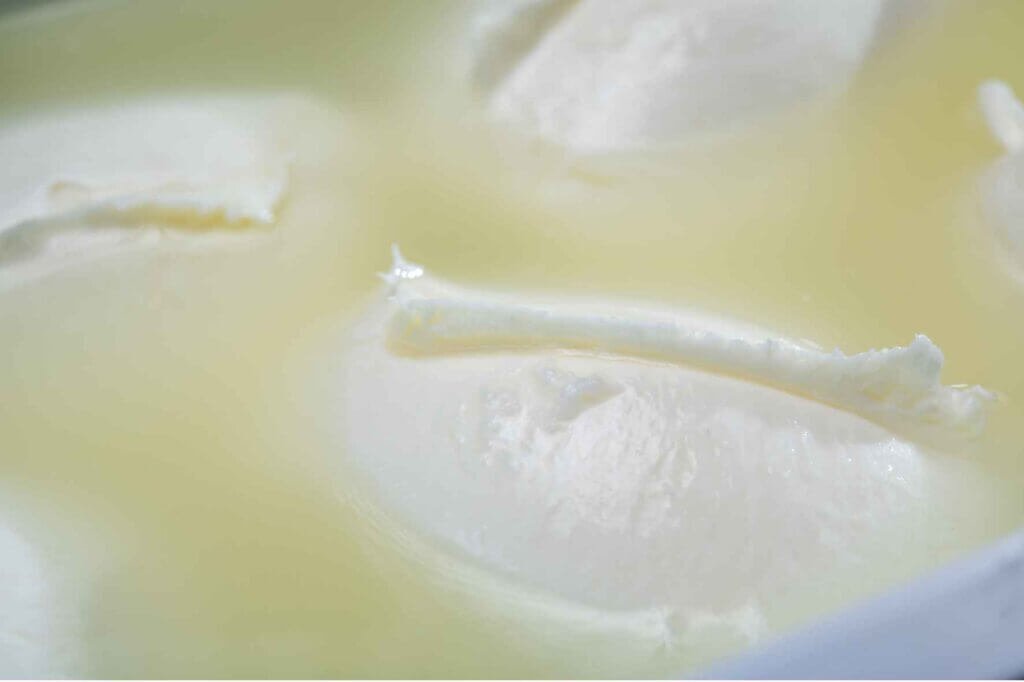 Fresh Akkawi cheese soaking in brine, showing its soft white texture during the preservation process.