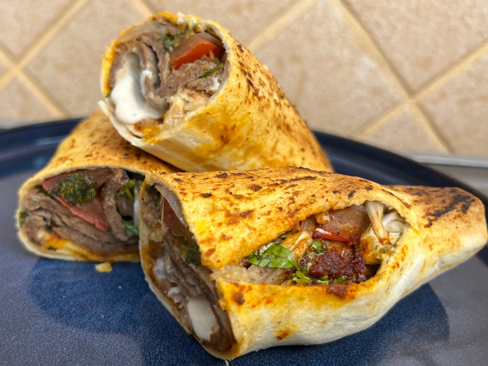 Close-up of homemade doner kebab wraps filled with seasoned beef, vegetables, and creamy sauce in toasted bread