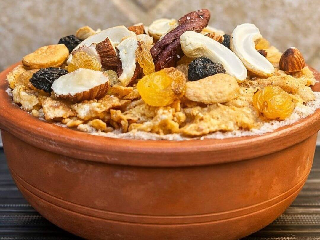 Umm Ali dessert served in a clay pot topped with mixed nuts, raisins, and dried fruits