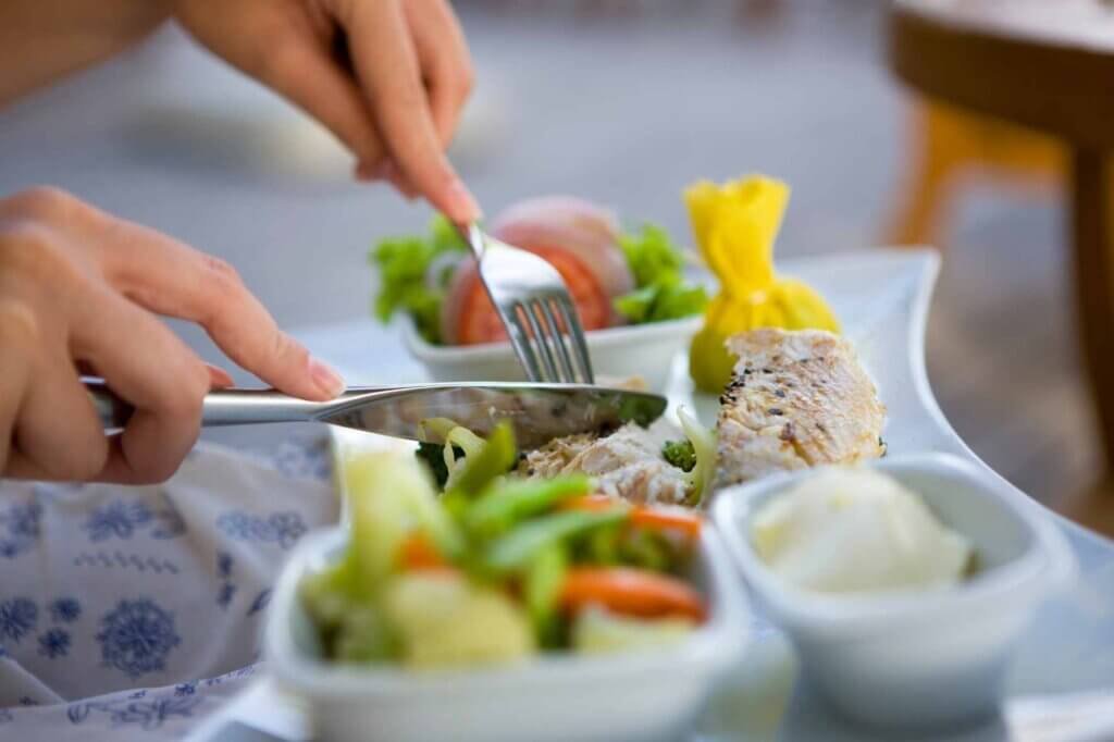 Person enjoying a healthy homemade meal with grilled chicken, steamed vegetables, mashed potatoes, and fresh salad.