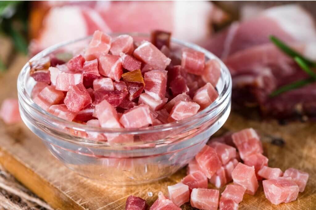 Bowl of diced ham ready to be used in a creamy pasta sauce in a professional kitchen.