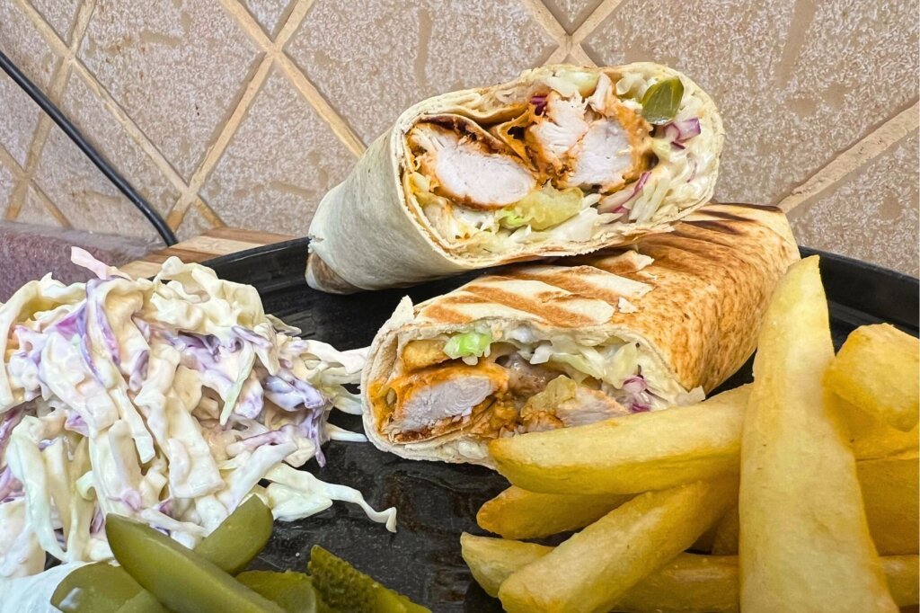 Grilled chicken tawook sandwich served with creamy coleslaw, crispy fries, and pickles