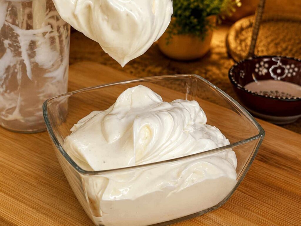 Creamy homemade mayonnaise with a thick, silky texture in a glass bowl