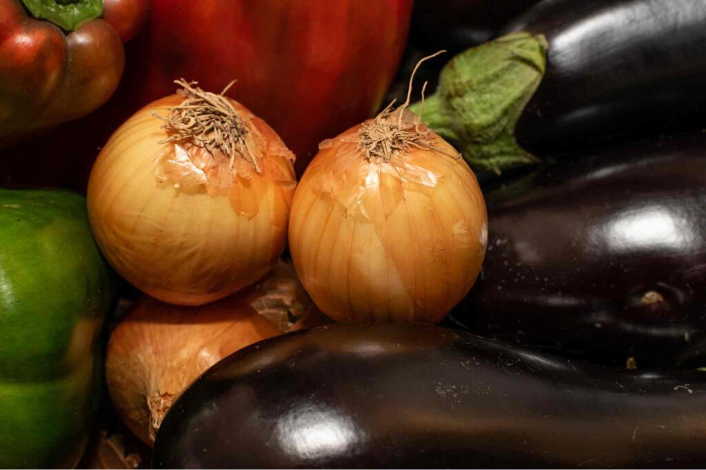 Onions and eggplants ready for preparation by a commis chef in a professional kitchen