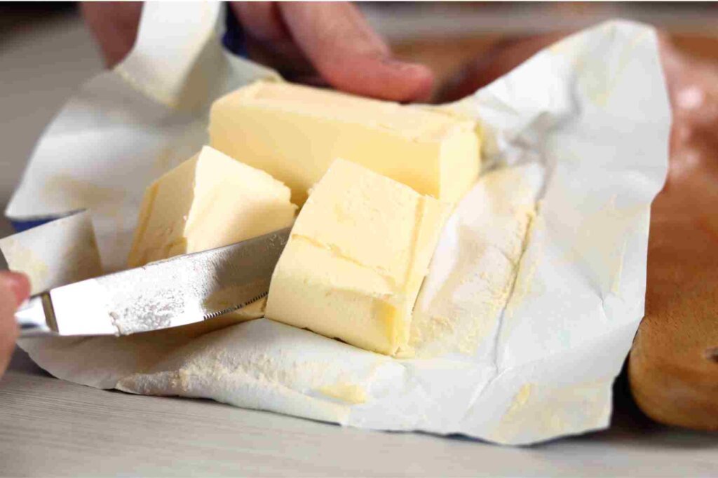 A chef cutting a block of butter into pieces for cooking and finishing restaurant dishes.