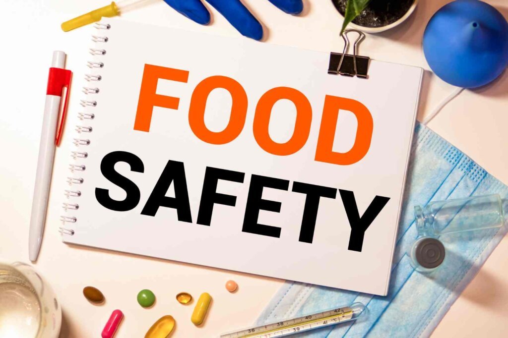 Food safety message on a notebook surrounded by kitchen hygiene and temperature-checking items