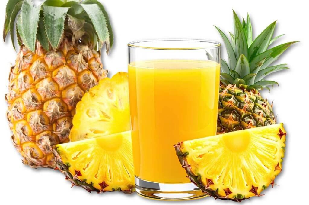 Glass of pineapple juice surrounded by fresh pineapples and pineapple slices
